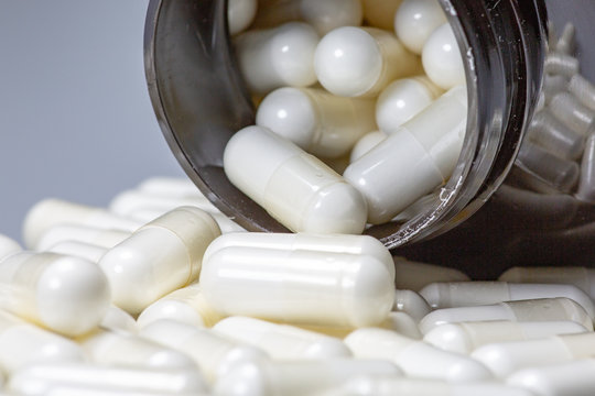 White Large Pills Falling Out Of A Large Brown Pill Bottle