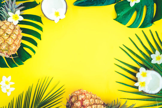 Fototapeta Summer flat lay frame with tropical green leaves, coco and pineapples frame on yellow background, retro toned