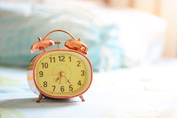Alarm clock on desk near the window with morning light and copy space