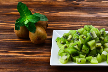 Freshly sliced kiwi fruit with whole kiwis in background.