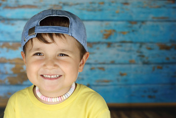 ni&ntilde;o con la gorra del rev&eacute;s con un collar de caramelos en un fondo azul