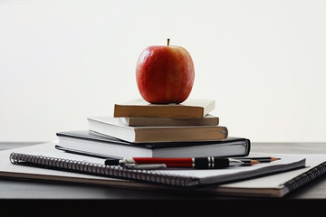 Apple, pile of books and school supplies on the table