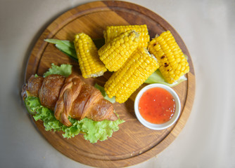 Grilled corn with croissant and sauce on the table