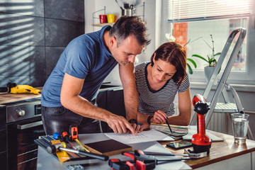 Couple looking at blueprints during kitchen renovation
