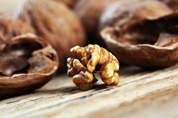 Walnut kernels and whole walnuts on rustic old table.