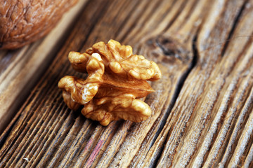 Walnut kernels and whole walnuts on rustic old table.