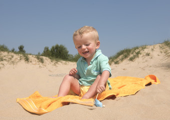 Two year old boy playing on the beach with a windmill