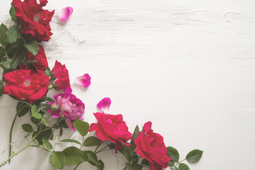 Bouquet of red roses on a white wooden surface, top view, copy space