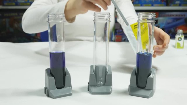 The scientist mixes colored liquids in chemical tube