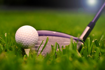  Macro shot of a golf club with ball and tee on the fairway grass with sun shining