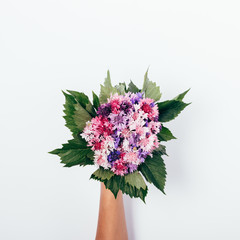 Flat lay composition of bunch of summer flowers with green leaves
