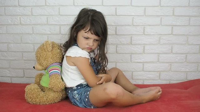 Child with a bear. The little girl takes offense at the toy.