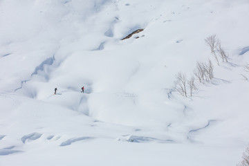 two tourists on the snowed sidehill of mountain. Alps, France, Bessans.