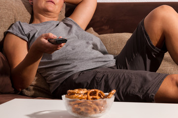 Frau mit TV Fernbedienung und Bretzeln