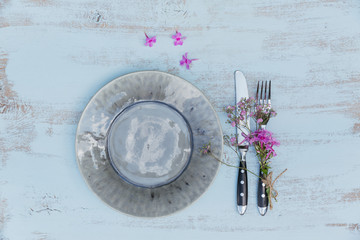 Rustic table setting with pink flowers on light wooden table.
