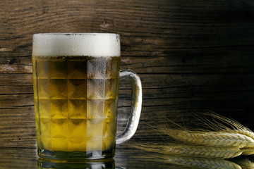 A mug of beer with droplets of condensate and barley ears