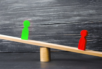 wooden figures of people. rivals in business stand on the scales. trial. conflict. victory and...