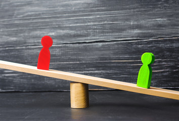 wooden figures of people. rivals in business stand on the scales. trial. conflict. victory and...
