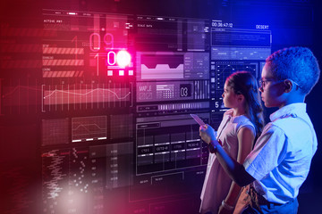 Using remote control. Calm concentrated child holding a modern remote control and showing his friend how to use it