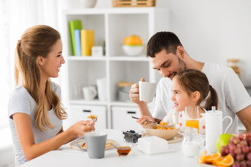 Obraz na płótnie Canvas family, eating and people concept - happy mother, father and daughter having breakfast at home