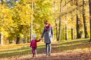 Fototapeta premium family, season and people concept - happy mother and little daughter walking along autumn park