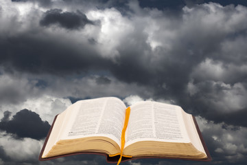 Open bible book on dramatic sky