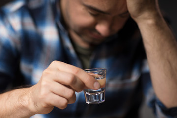 alcoholism, alcohol addiction and people concept - close up of male alcoholic drinking vodka shot at night
