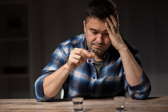 alcoholism, alcohol addiction and people concept - male alcoholic drinking shot at night