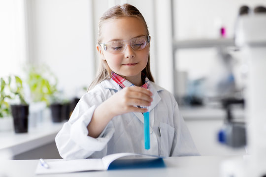 education, science and children concept - girl in goggles with test tube studying chemistry at school laboratory