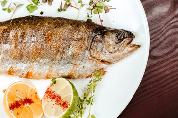 Fried fish on a wooden background. With lemons and spices.