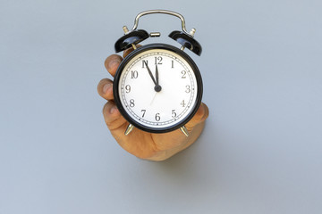 Time is Running Out. Large Classic Alarm Clock in a Hand.