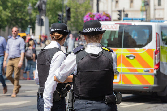 London, England, UK; 13th July 2018; Rear view of Two Female Metropolitan Police Officers in the Street.  Unfoccused Police Van Behind