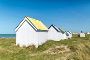 Fototapeta na wymiar Colorful wooden beach cabins in the dunes, Gouville-sur-Mer, Normandy, France