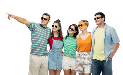 friendship, summer and people concept - group of happy smiling friends in sunglasses hugging over white background and pointing finger to something