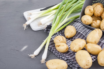 Young potatoes, green onions on a table for cooking dinner. Vegetables for healthy eating. Copy space,