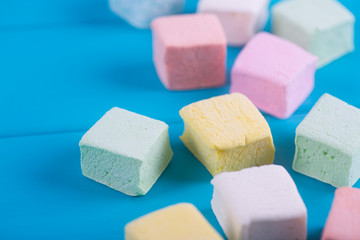 Closeup square colorful pastel marshmallow set on vibrant blue background.