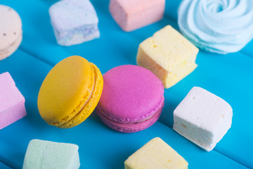Closeup colorful macaroons and different marshmallow on on vibrant blue background.