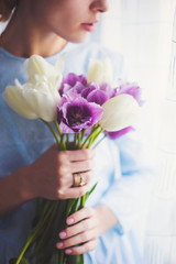 Young tender girl holding beautiful spring bouquet of purple and white tulips