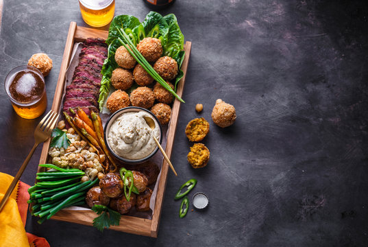 Middle eastern or arabic dishes and assorted meze on a dark background. Meat, falafel, baba ghanoush, vegetables. Halal food. Copyspace. Top view