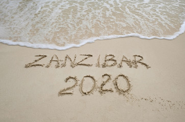 Zanzibar 2020 year description on light sand with waves