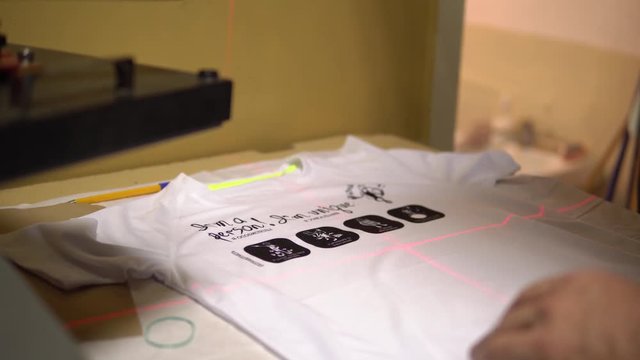 Make a print on t-shirts. The operator puts a t-shirt under the laser for marking and imposes a print. T-shirt printing, thermal printing