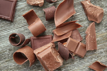 Pieces of chocolate with curls on wooden table