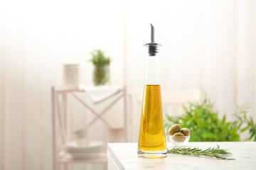 Bottle with fresh rosemary oil on table