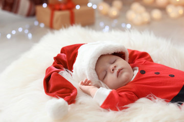 Cute baby in Christmas costume sleeping on fur rug