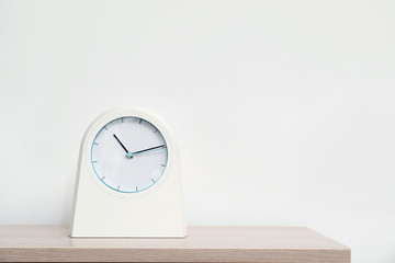 Modern clock on table against light background. Time concept
