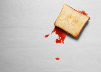Overturned toast bread with jam on floor, top view