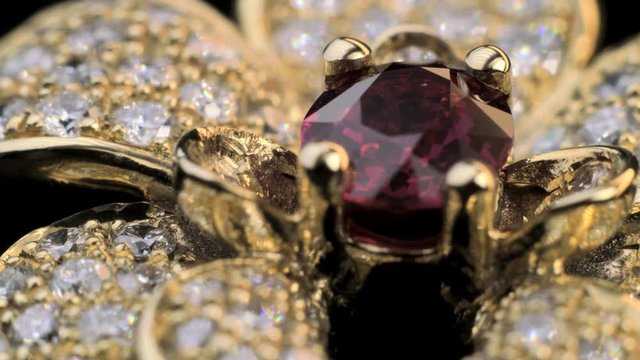 Amazing stunning ring with red ruby in gold jewelry with many sparkling and shining diamonds. Close up shot of beautiful, expensive and luxury jewel.