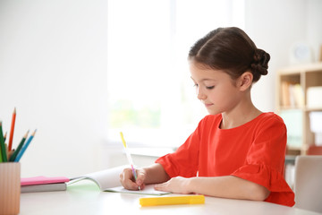 Cute little child doing assignment at desk in classroom. Elementary school