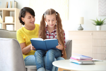 Young woman helping her child with homework at home. Elementary school