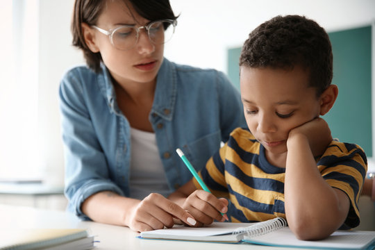 Female Teacher Helping Child With Assignment At School